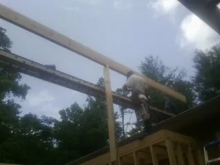 Carpenter setting a ridge beam over a new addition frame — Ice Dam Removal by Roofing Brothers in Price