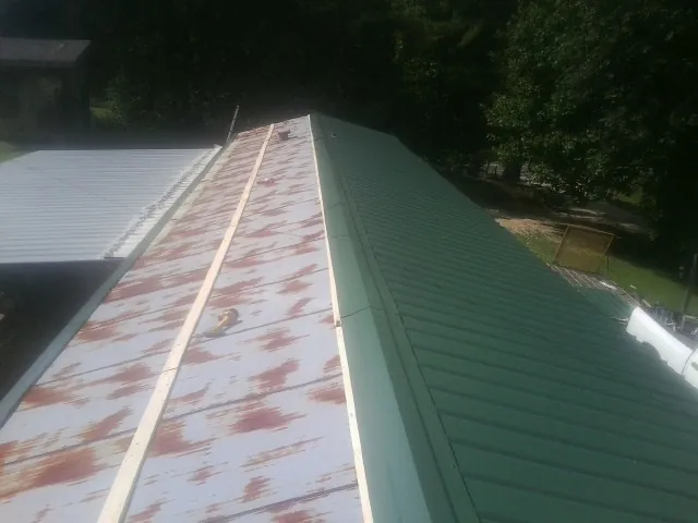 Old rusted panels beside newly installed green metal roofing — Wind Damage Roof Repair by Roofing Brothers in Price