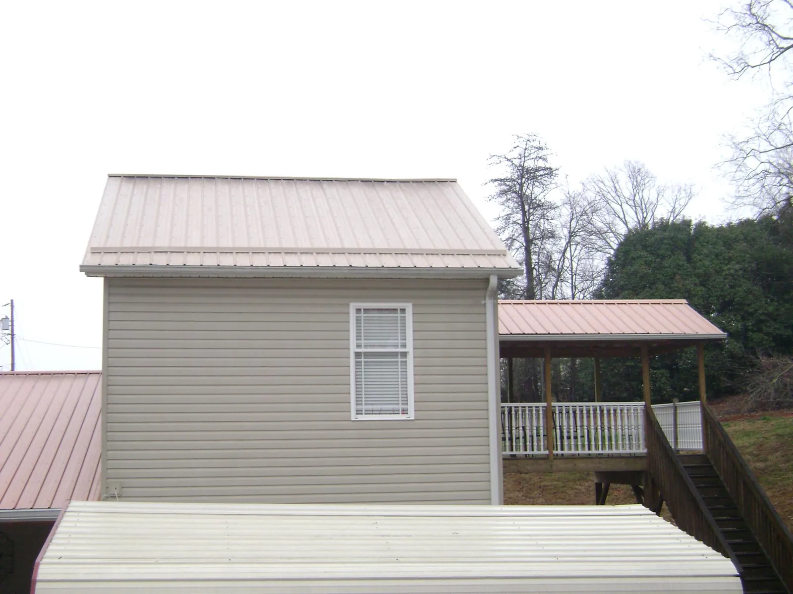 Tan metal roofs on a two story addition and attached porch, from a Roof Replacement job in Price